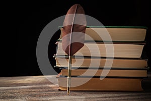 Closeup of fountain pen near stack of old books against black background