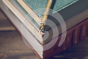 Closeup of fountain pen on stack of old books. Selective focus.