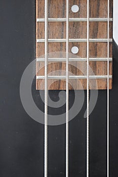 Closeup of four bass strings and black pickups on a grey swamp ash bass body