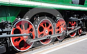 Closeup of four big red driving wheels of a steam locomotive