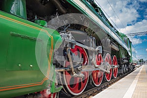 Closeup of four big red driving wheels of a steam locomotive