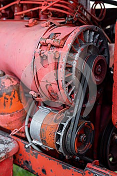 Closeup of four cylinder diesel tractor engine with visible belt rusty tracks hydraulic parts and wiring red paint in sunny autumn