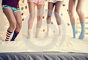 Closeup of four pairs of teen legs with socks jumping on the bed