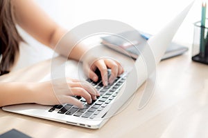 Closeup freelance asian woman working and typing on laptop computer at desk office with professional