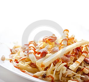 Closeup of french fries served in restaurant plate isolated on white background. Fried potato with ketchup, cheese and bacon