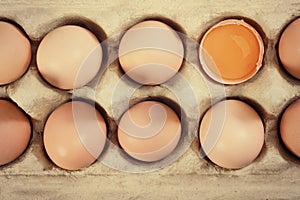 Closeup of fresh brown eggs in carton tray. Top view, tinted photo