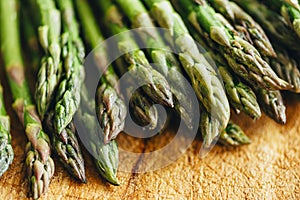 Closeup of fresh green asparagus on vintage wooden table. Cooking vegetarian food with organic ingredient on rustic board. Healthy