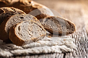 Closeup of fresh slices of organic homemade bread loafs on a rustic cloth and wooden table