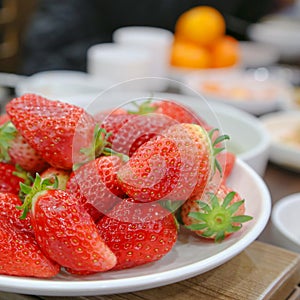 Closeup fresh strawberries in white ceramic plate on dark background (soft focus on stawberry at middle frame)