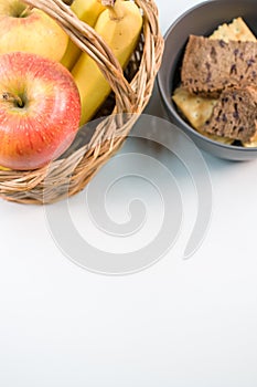 Closeup of fresh tasty organic bananas with an apple  and bowl on a blank surface