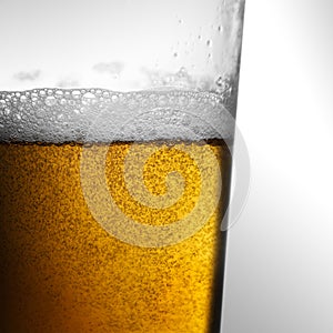 Closeup of freshly poured glass of beer with frothy head and bubbles photo
