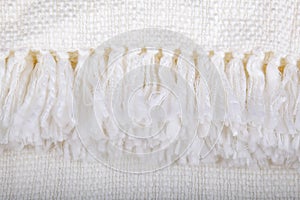 Closeup fringe on soft knit throw blanket is crisp white.