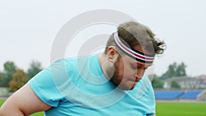 Closeup in front of the camera obese man at the starting line at the stadium outside start to run he want to loose the