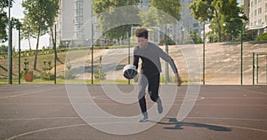 Closeup front portrait of young attractive African American male basketball player throwing a ball into a hoop outdoors