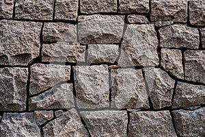 Closeup front view of a massive stone wall with sharp lines outdoors.