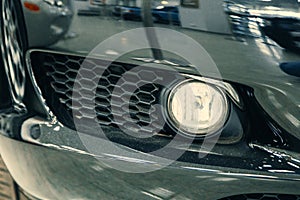 Closeup front xenon fog headlights of modern car in garage