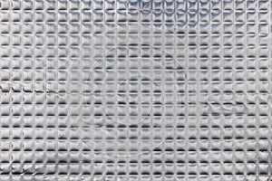 Closeup full-frame background and texture of aluminum coated butil rubber sheet with square pattern.