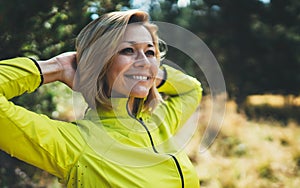 Closeup fun girl exercising outdoors in sun summer day, smile fitness woman stretching exercises training outside in park