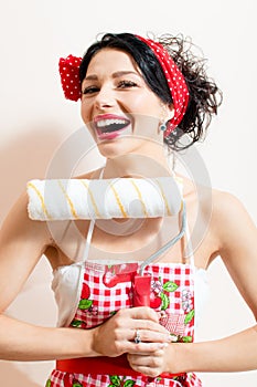 Closeup on funny brunette pinup pretty girl holding paint bolster, having good time & fun looking at camera and laughing