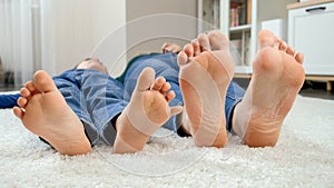 Closeup funny shot of barefoot family lying on carpet and moving feet