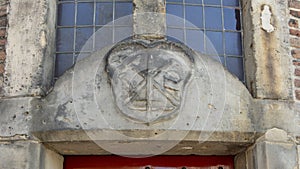 Closeup of the Gable Stone for the Blacksmith`s Guild above a red door, Waag House, Amsterdam, The Netherlands