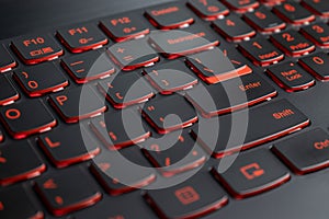 Closeup of gamer laptop keyboard red illumination, backlit keyboard, english letters