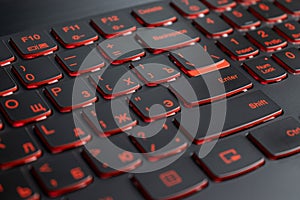 Closeup of gamer laptop keyboard red illumination, backlit keyboard, russian letters