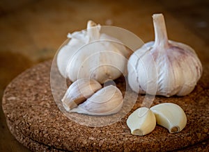 Closeup of garlic bulb and cloves on a round cork board