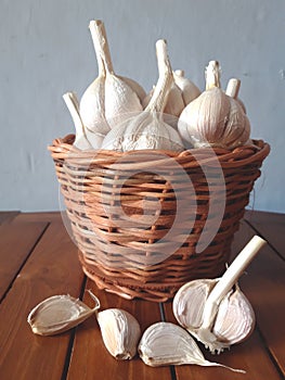 Closeup garlic are in the wicker basket on the wooden table