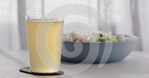 closeup ginger beer in a tumbler glass on oak table with blue bowl on background