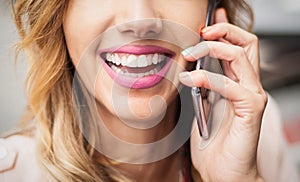 Closeup of girl with beautiful teeth, talking on her smartphone