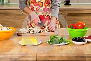 Closeup of girl hands cutting the mushrooms in the kitchen