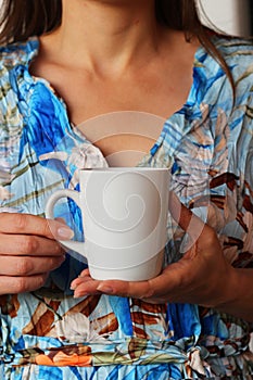 Closeup of girl holding blank white coffee mug mockup. White mug mock up for your company logo and design