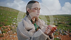 Closeup girl peeling apple on green hill. Contemplative traveler rest mountains