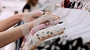 Closeup of girl`s hand in a clothing store choosing a stylish summer dress. shopping at women`s clothing showroom