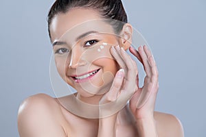 Closeup glamorous woman applying moisturizer cream on her face for perfect skin