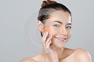 Closeup glamorous woman applying moisturizer cream on her face for perfect skin