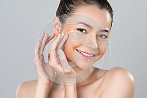 Closeup glamorous woman applying moisturizer cream on her face for perfect skin