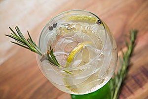 Closeup glass Alcoholic drink gin and tonic cocktail with lemon, rosemary and ice on rustic black stone table