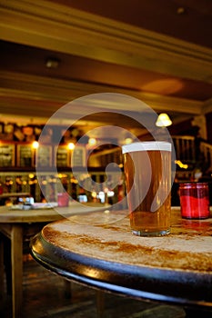 Closeup of a glass of beer on the table under the lights in the bar with a blurred background