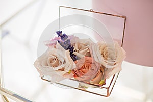 Closeup glass box for wedding rings decorated with fresh rose flowers and banch of lavender. Event decoration with fresh flowers