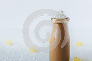 Closeup of a glass of chocolate milkshake on a table, with cream on top