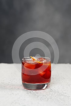 Closeup glass of cosmopolitan cocktail decorated with orange at greay wall background with copyspace photo