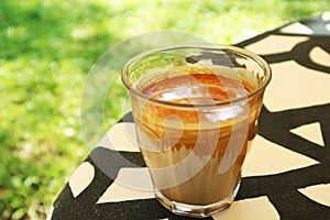 Closeup of a Glass of Dirty Latte Coffee on a Garden Table