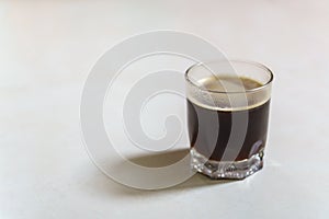 Closeup of glass of hot black coffee Americano with sunlingt and shadow on white table