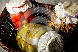 closeup glass jars with homemade canned vegetables lie in basket