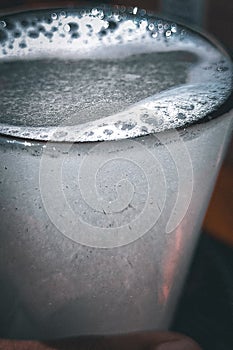 Closeup of glass of lemon soda water with bubbles froth