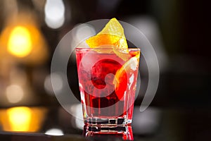 Closeup glass od red alcoholic cocktail decorated with lemon at