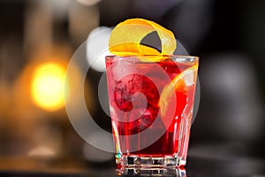 Closeup glass od red alcoholic cocktail decorated with lemon