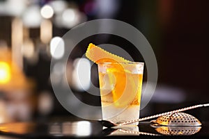 Closeup glass of old fashioned cocktail decorated with orange